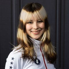 A portrait of Alyssa Liu smiling, wearing a white Team USA athletic jacket.