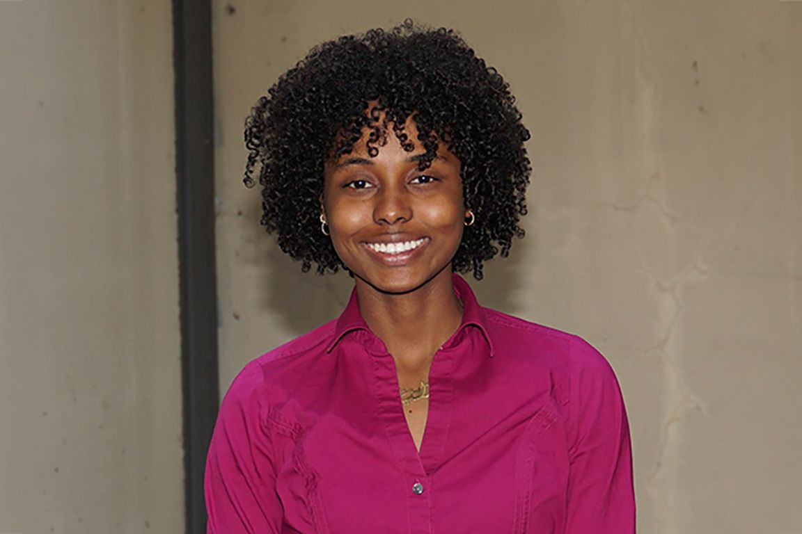 A portrait of Rania Gomaa-Mersa smiling, wearing a magenta button-down shirt.