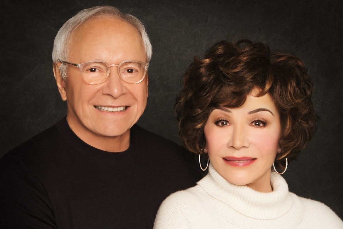 Stewart and Lynda Resnick smile together in a formal portrait against a dark gray background.