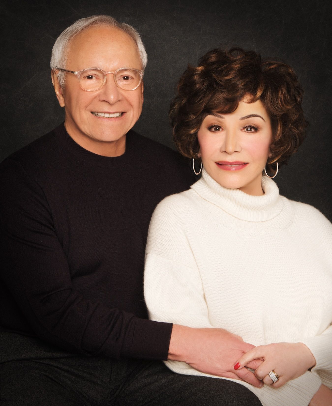 Stewart and Lynda Resnick smile together in a formal portrait against a dark gray background.
