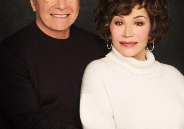 Stewart and Lynda Resnick smile together in a formal portrait against a dark gray background.