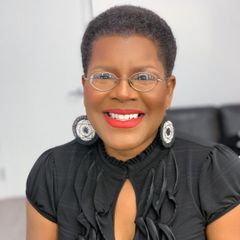 Tananarive Due smiles in a portrait photo wearing a black ruffled top and large circular earrings.