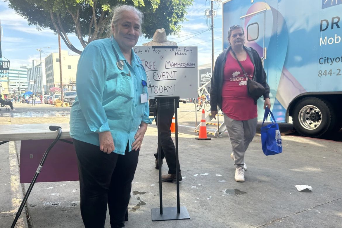 Two women stand outdoors near a sign reading "City of Hope + UCLA Family Medicine Free Mammogram Event Today!" with a City of Hope mobile mammography unit visible in the background.