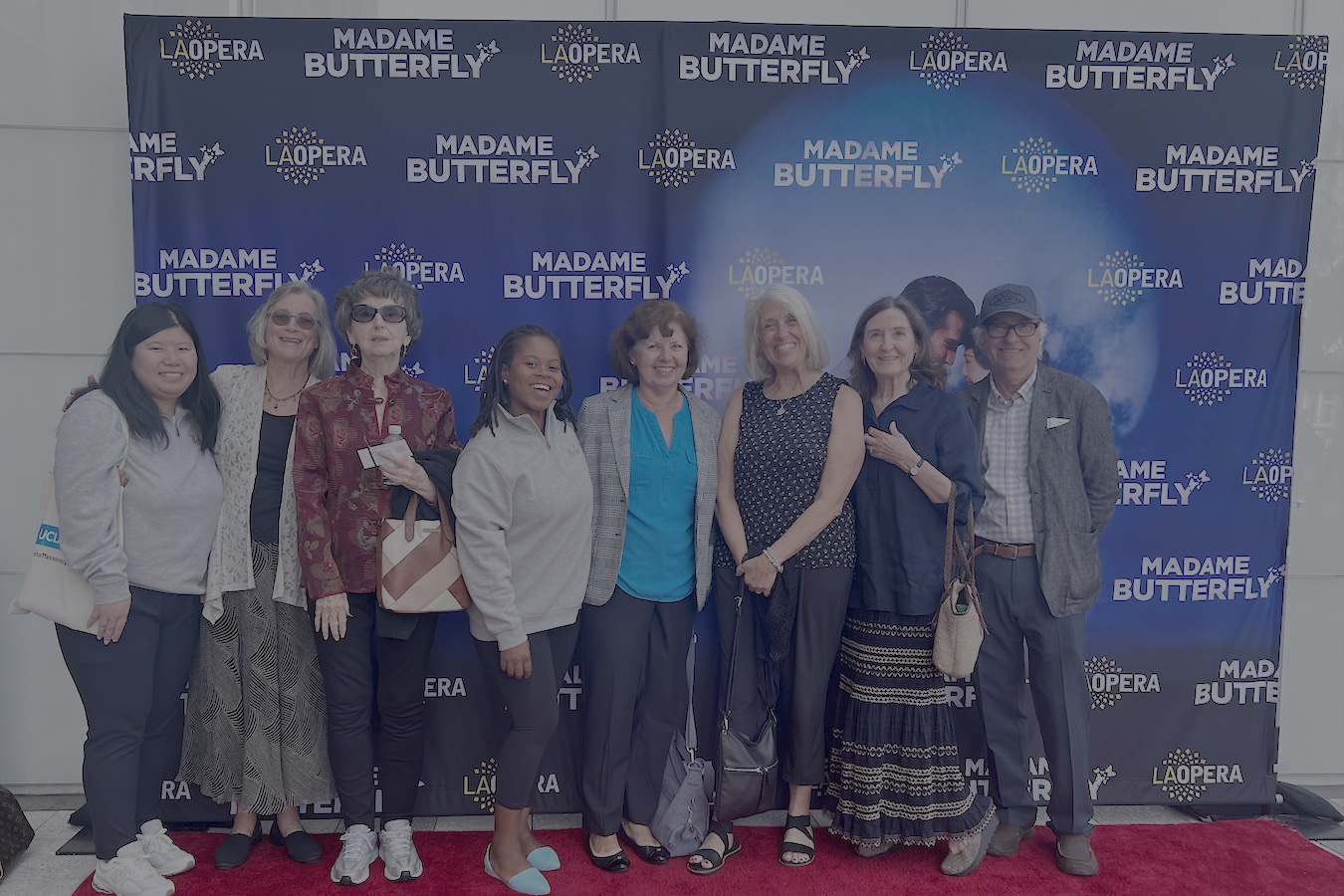 Several members of UCLA's retiree community pose in front of "Madame Butterfly" poster at the Los Angeles Opera.