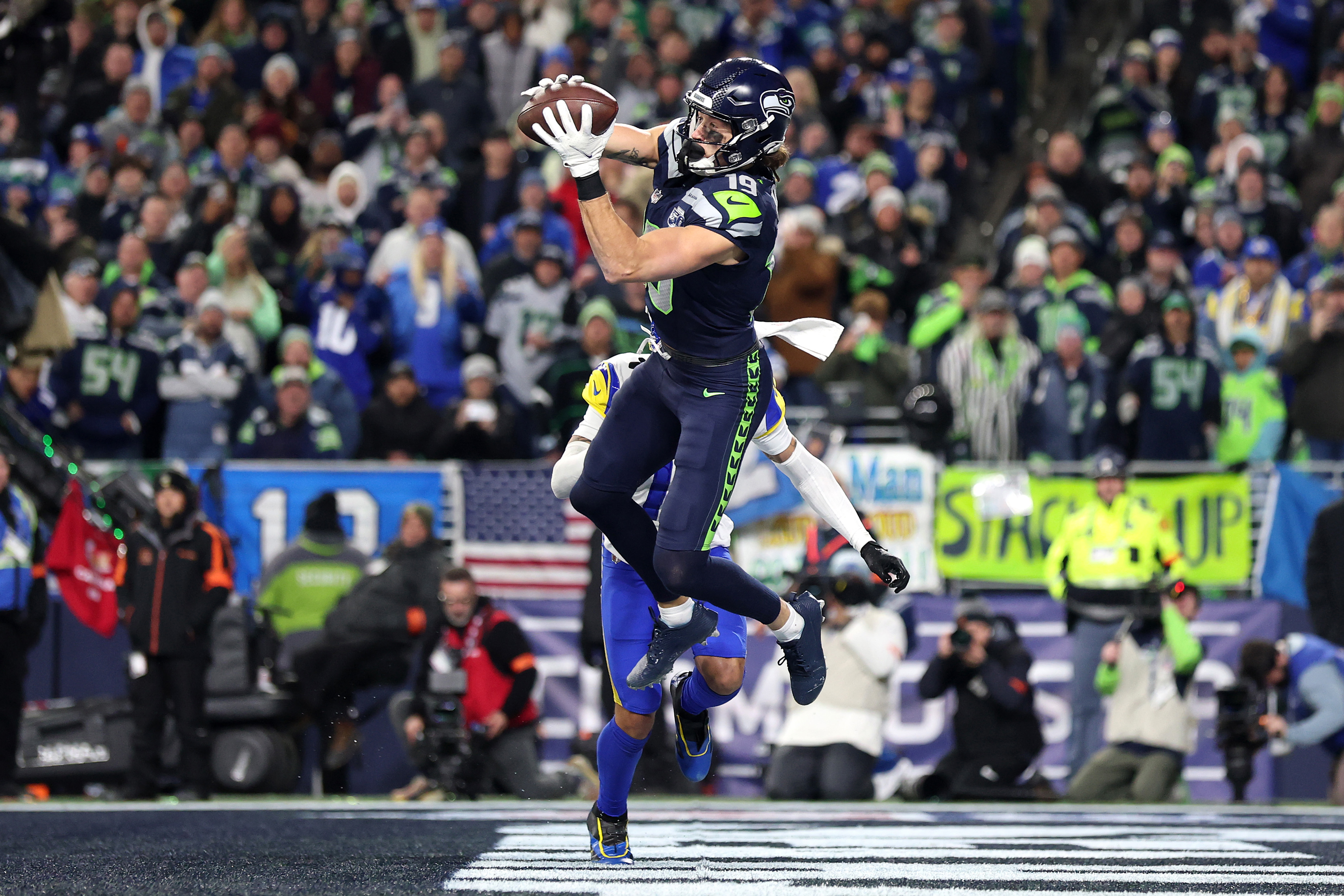 Seattle Seahawks wide receiver Jake Bobo leaping to catch a pass during an NFL game before a packed crowd.