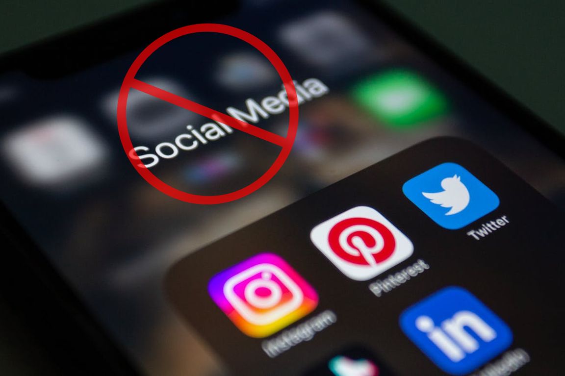 A smartphone screen displaying social media app icons including Instagram, Pinterest, Twitter, and LinkedIn, overlaid with a red prohibition symbol and the words "Social Media."