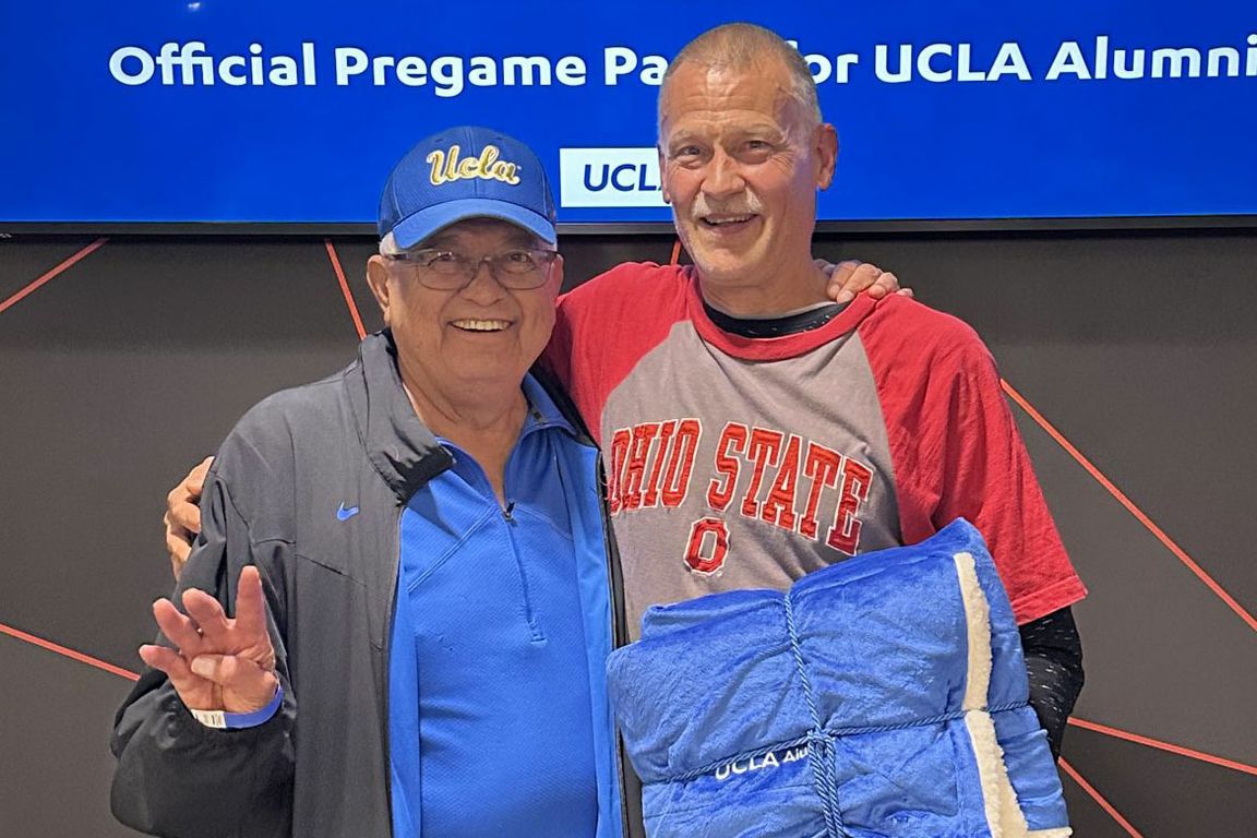 Hernando Marroquin (left), wearing a UCLA cap, and Dave Jessen (right), wearing an Ohio State shirt, smile together at a UCLA Alumni pregame party