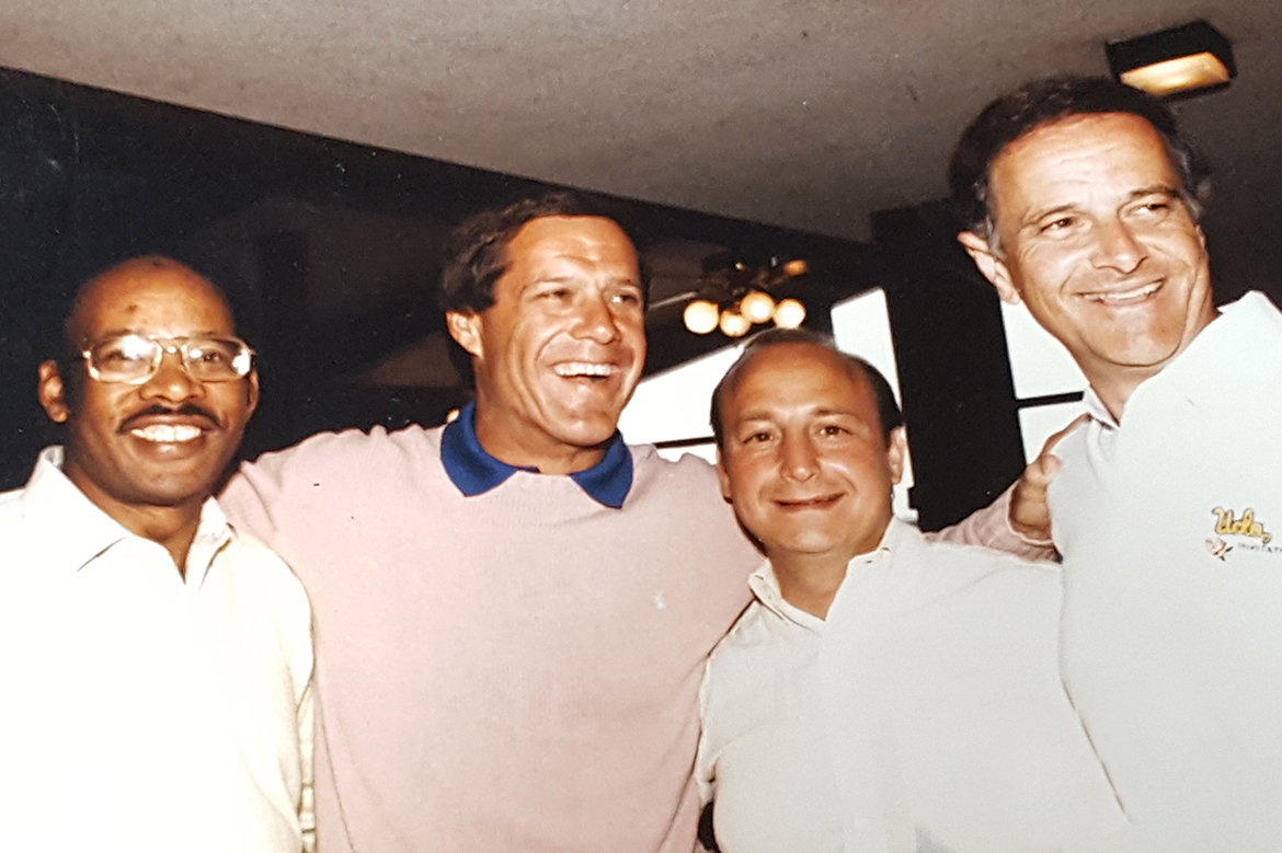 Midrange photo of four men with their arms around each other