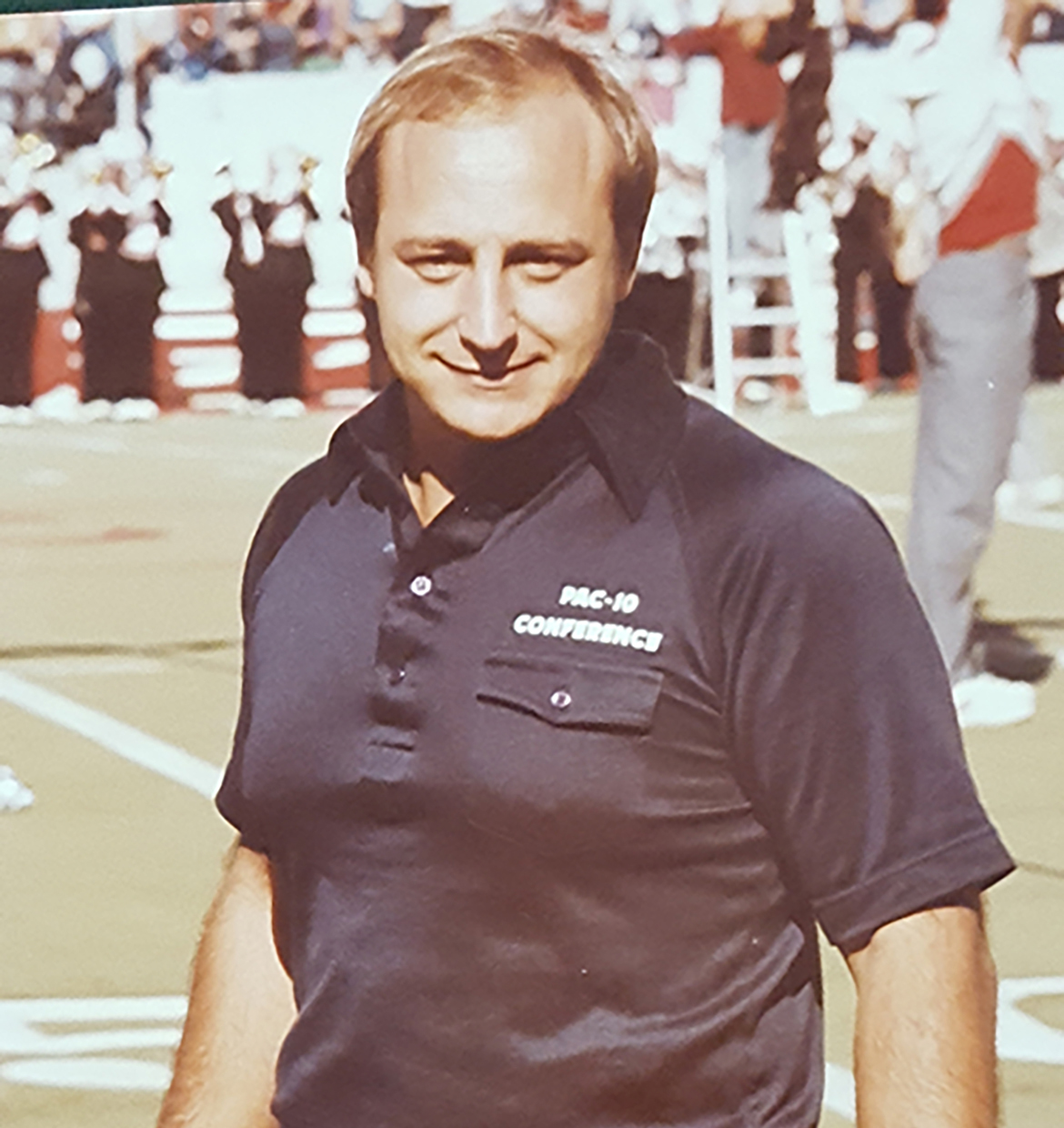 Angelo Mazzone in dark blue polo shirt with PAC-10 Conference in white letters