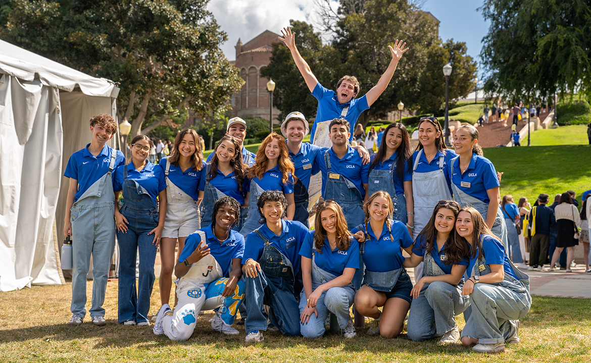 A large group of helpers pose energetically on a campus lawn during Bruin Day.   