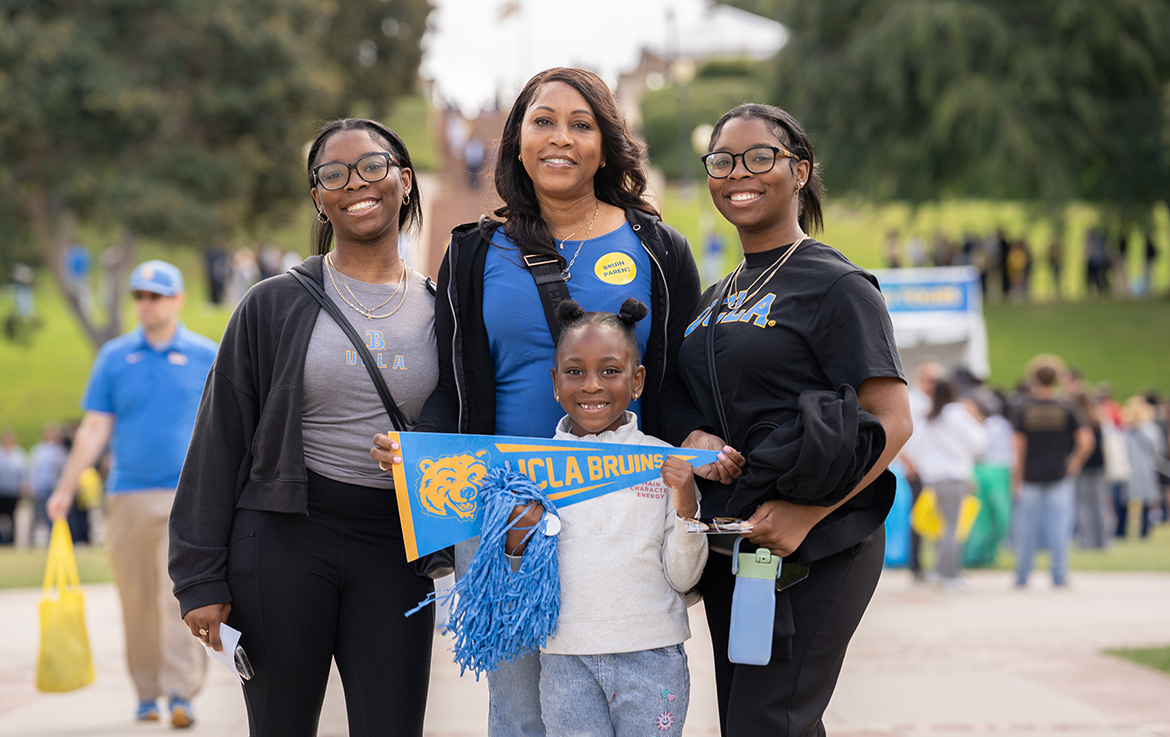 A smiling family of four poses together on the UCLA campus during Bruin Day.