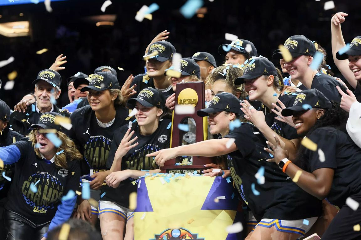 The UCLA women's basketball team celebrates with the NCAA Championship trophy amid a shower of confetti, wearing "National Champs" hats and gear. 