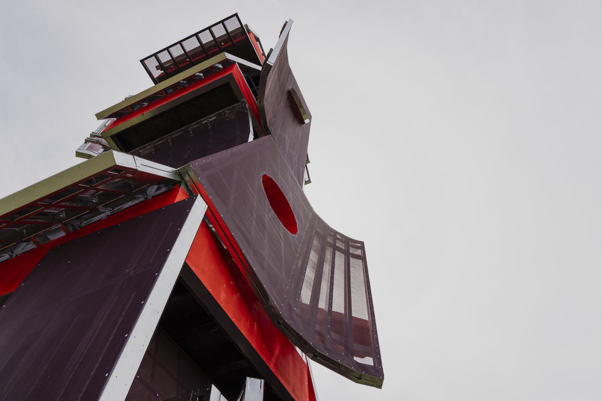 Photo looking up at brown, red and green sculpture made of four geometric boxes