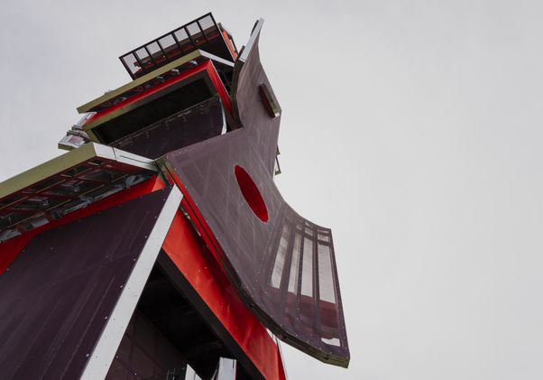 Photo looking up at brown, red and green sculpture made of four geometric boxes