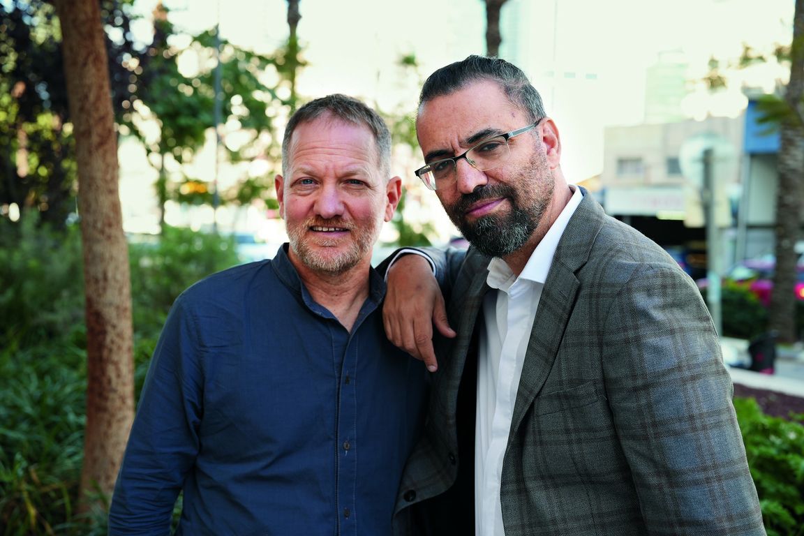 Maoz Inon (left) and Aziz Abu Sarah pose together outdoors, with Abu Sarah's arm resting on Inon's shoulder. 