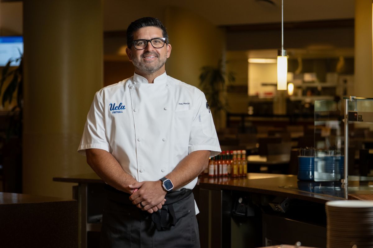 Joey Martin stands for portrait in white chef jacket  