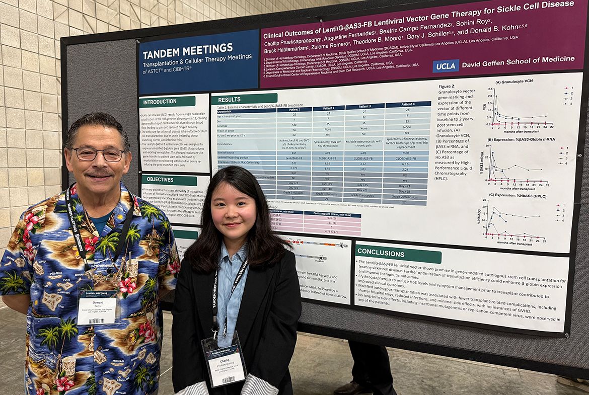 Donald Kohn, left, in Hawaiian shirt and Chattip Prueksapraopong, in black jacket and light blue button-down, stand in front of a presentation board