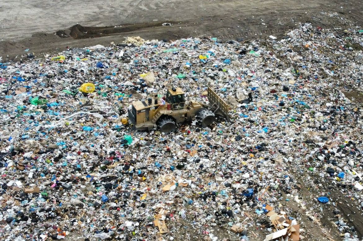 Aerial view of waste and garbage being flattened by heavy machinery