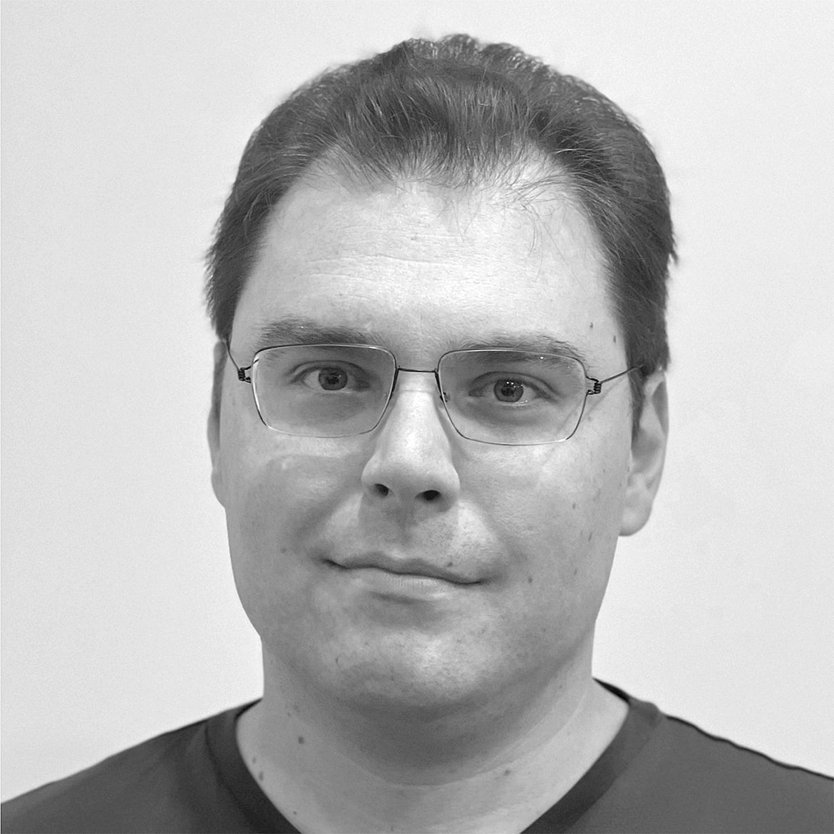 Black-and-white close-up of Thomas Dumitrescu wearing dark T-shirt and glasses