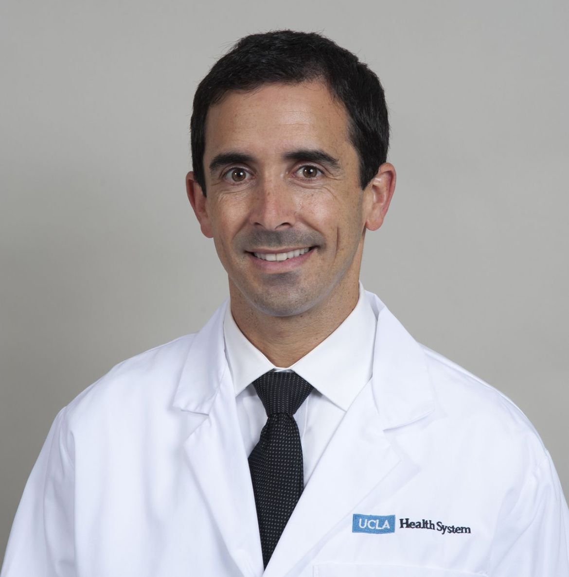 Head-and-shoulders photo of Jonathan Bergman in white coat and dark tie