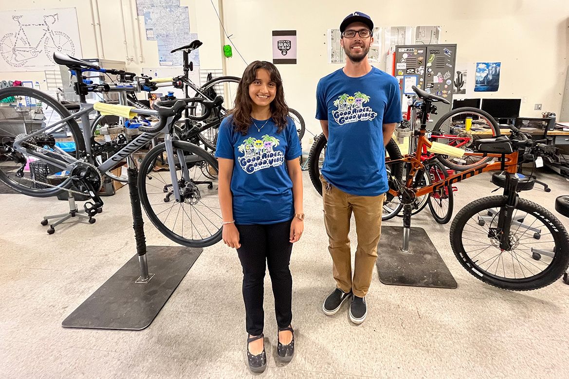Sana Ahmed, left, in blue T-shirt and black pants, and Martin Espinoza, in blue T-shirt and brown pants, standing in a room with bicycles