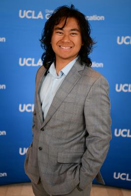 Christian Gerard Capuno in gray checkered suit standing in front of blue UCLA backdrop 