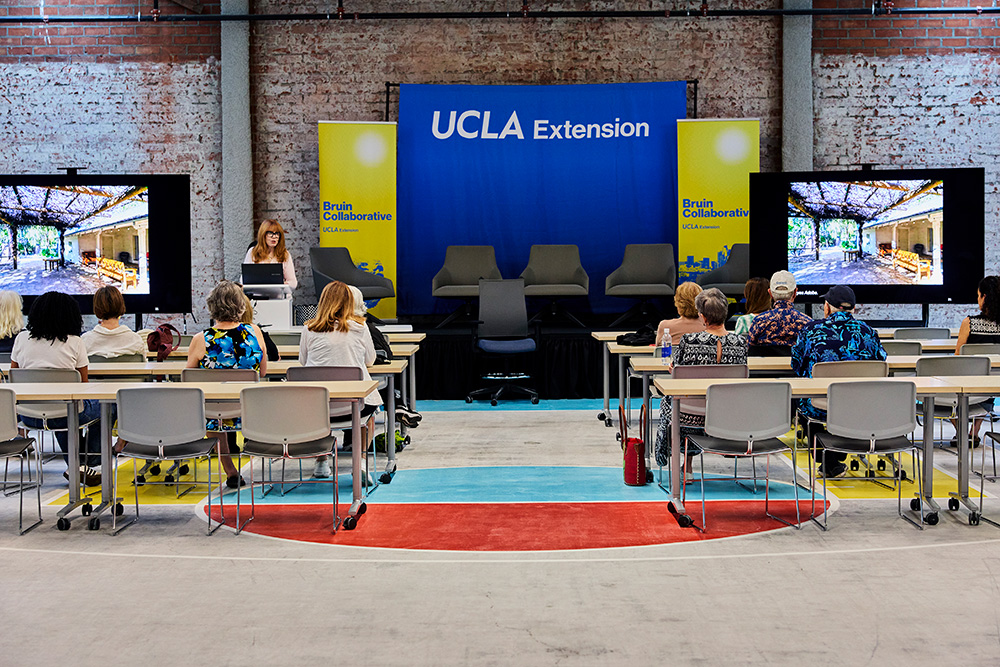 Eleanor Schrader teaches a class in a building with brick walls and a blue UCLA Extension sign
