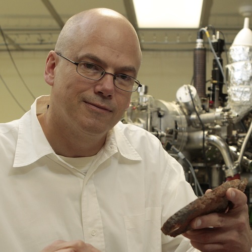Close shot of Craig Manning in white collared shirt holding a piece of rock.