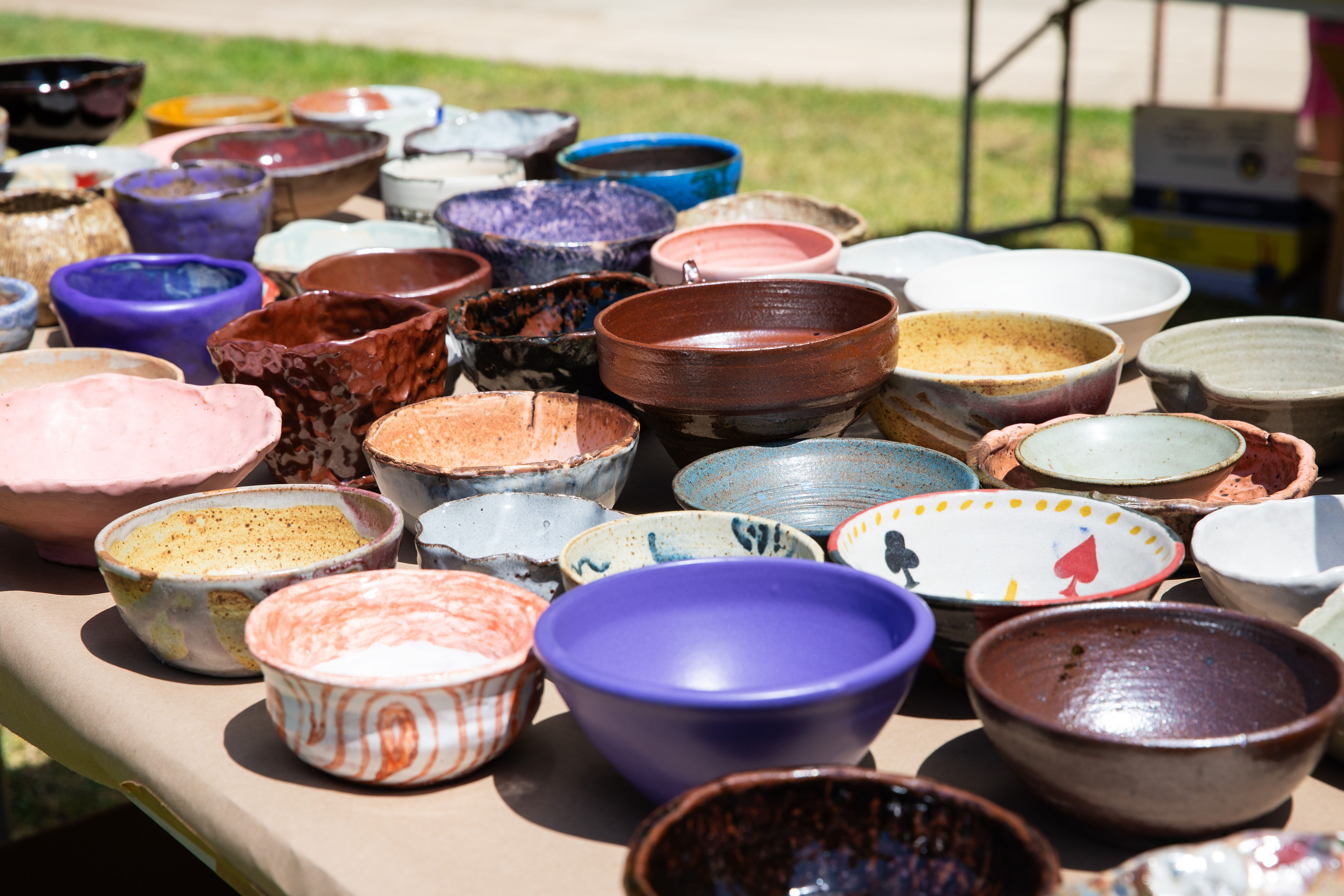 Dozens of colorful ceramic bowls lined up on a table