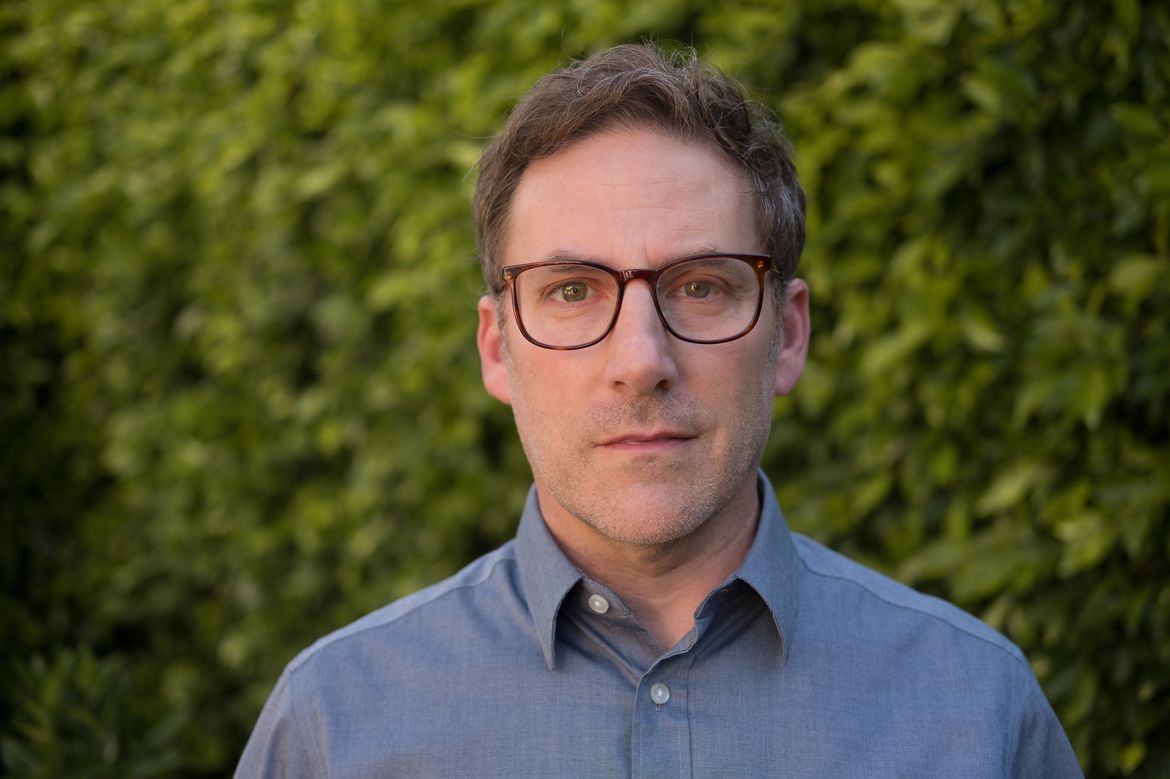 Head-and-shoulders photo of Stuart Soroka in front of green foliage wearing blue button-down and glasses 
