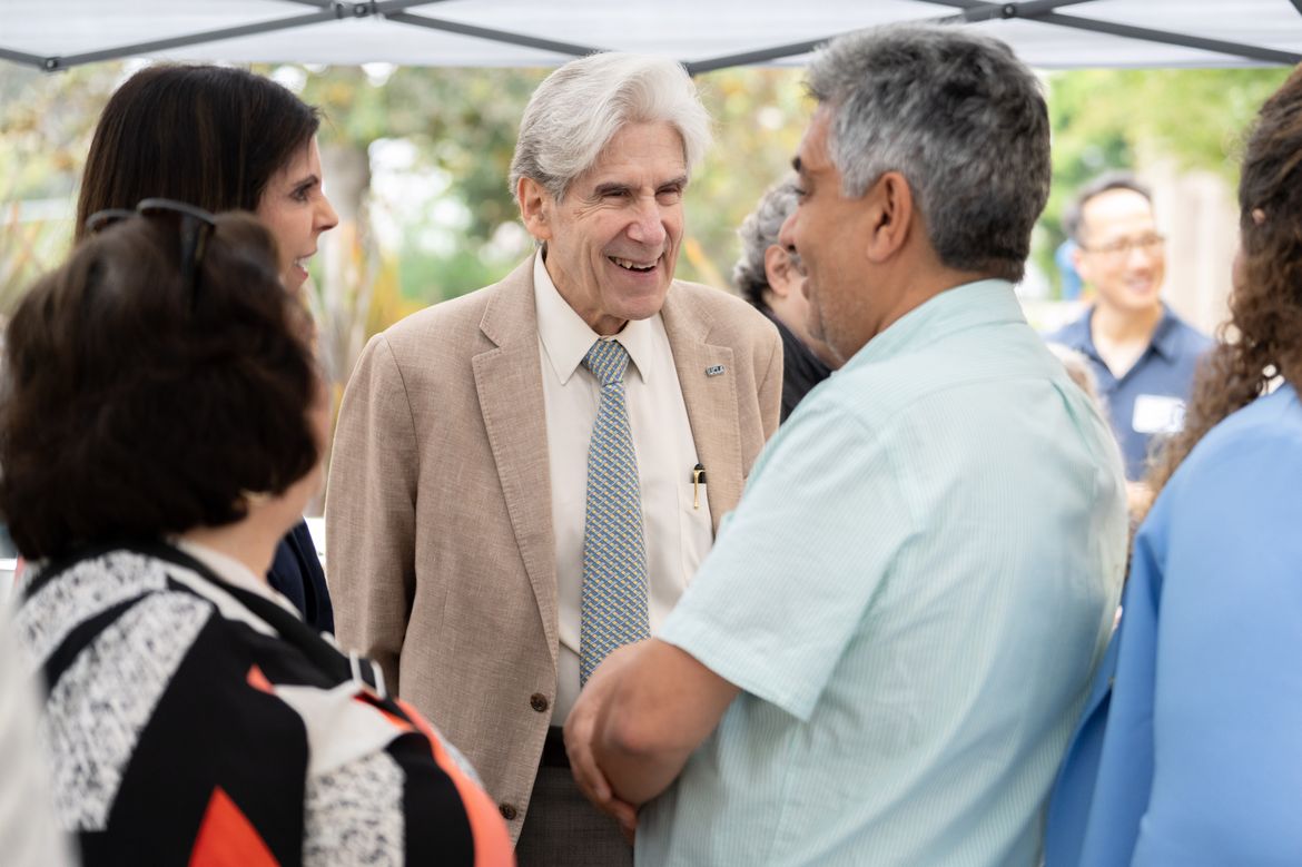 UCLA Chancellor Julio Frenk speaks with members of the Westwood and neighboring Los Angeles communities during a gathering under an outdoor canopy.