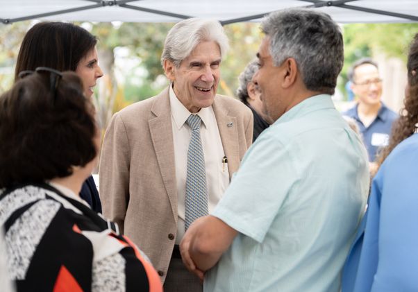 UCLA Chancellor Julio Frenk speaks with members of the Westwood and neighboring Los Angeles communities during a gathering under an outdoor canopy.