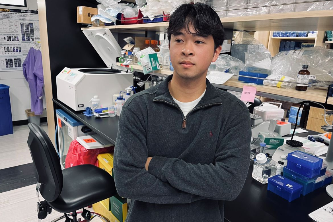 Aidan Lee stands with arms crossed in a lab