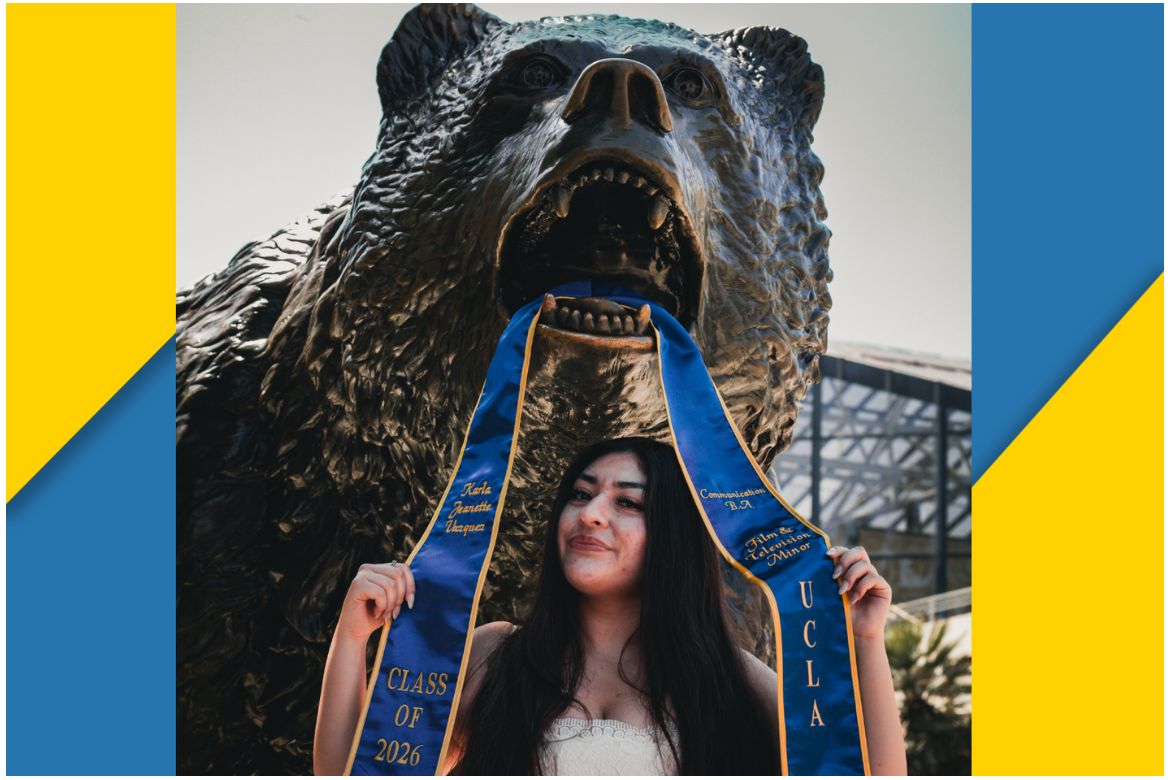 Karla Vasquez stands with blue graduation sash above head in mouth of bronze Bruin statue surrounded by blue and gold chunk border