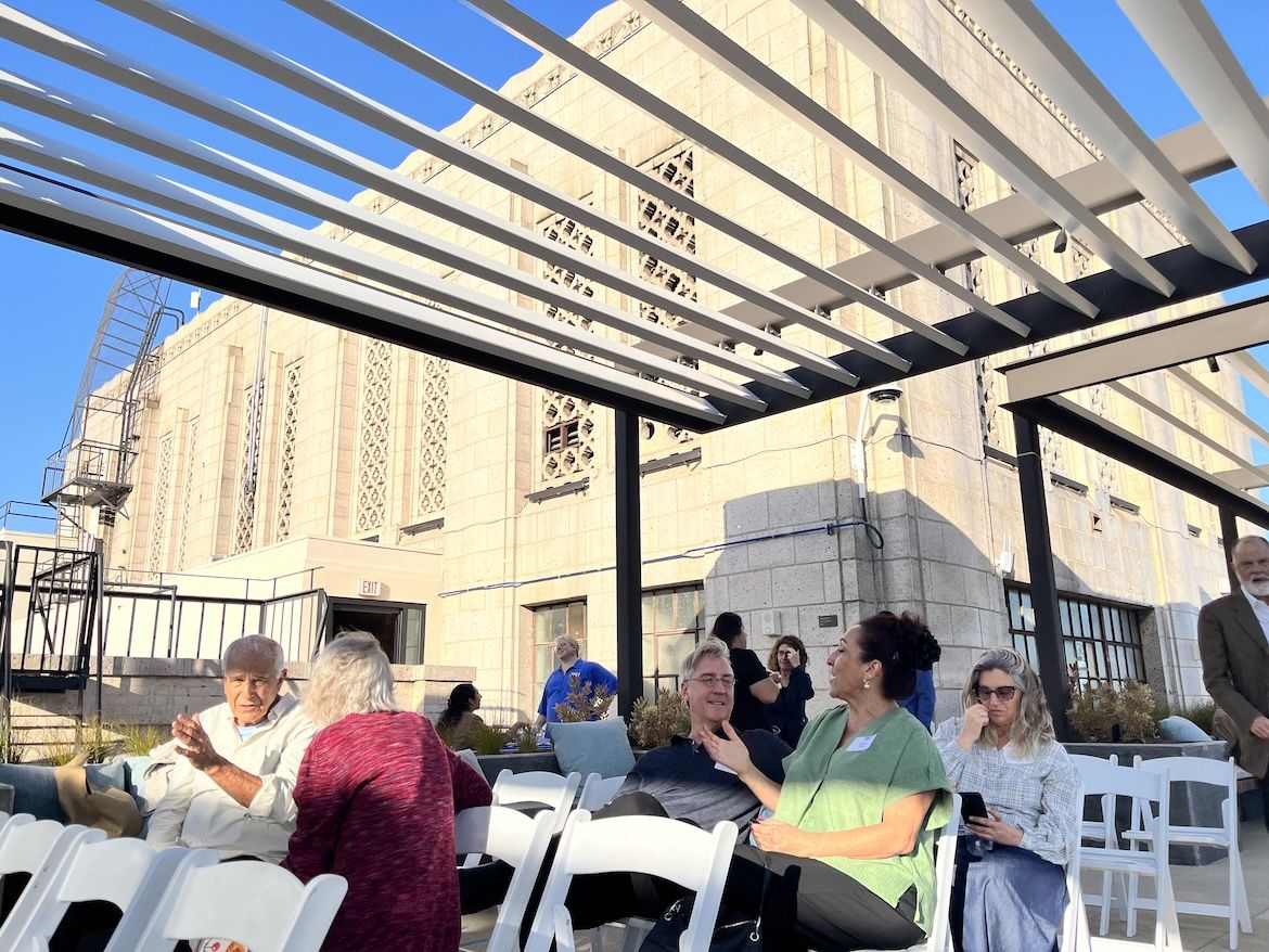 Attendees gather beneath a rooftop pergola at UCLA Downtown before Blueprint magazine's 10th anniversary conversation, with the historic Art Deco building providing a dramatic backdrop.