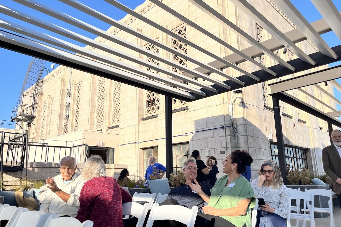 Attendees gather beneath a rooftop pergola at UCLA Downtown before Blueprint magazine's 10th anniversary conversation, with the historic Art Deco building providing a dramatic backdrop.