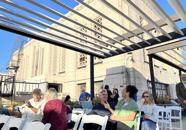 Attendees gather beneath a rooftop pergola at UCLA Downtown before Blueprint magazine's 10th anniversary conversation, with the historic Art Deco building providing a dramatic backdrop.