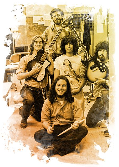 Sepia-toned group photo of five band members posing indoors with guitars and drumsticks. One person sits cross-legged in front while the others stand or kneel, surrounded by a paint-splatter border effect.