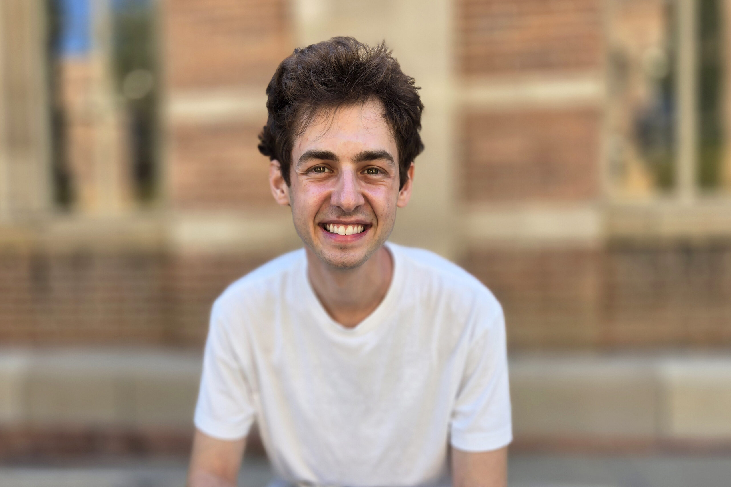 Head-and-shoulders shot of Benjamin Krut seated outside in white T-shirt, smiling