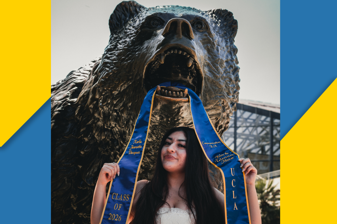 Karla Vasquez stands with blue graduation sash above head in mouth of bronze Bruin statue surrounded by blue and gold chunk border