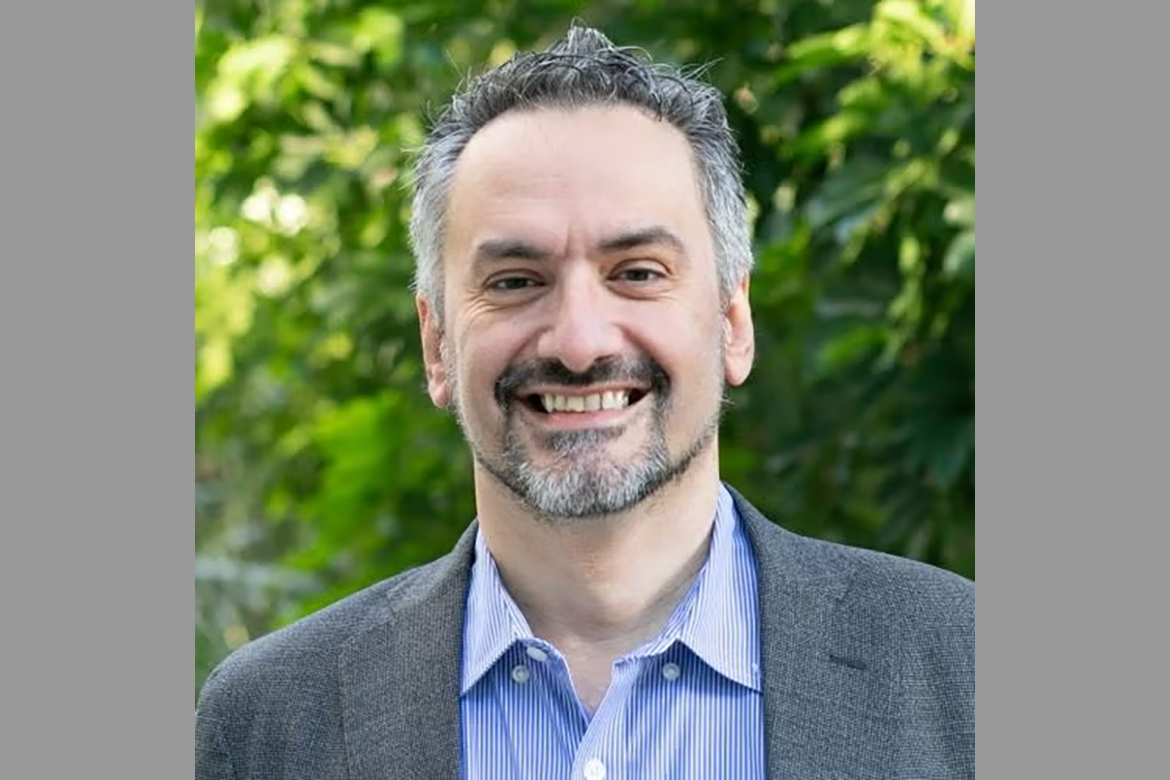 Head-and-shoulders photo of Michele Guindani wearing white-and-blue striped button-down and gray jacket