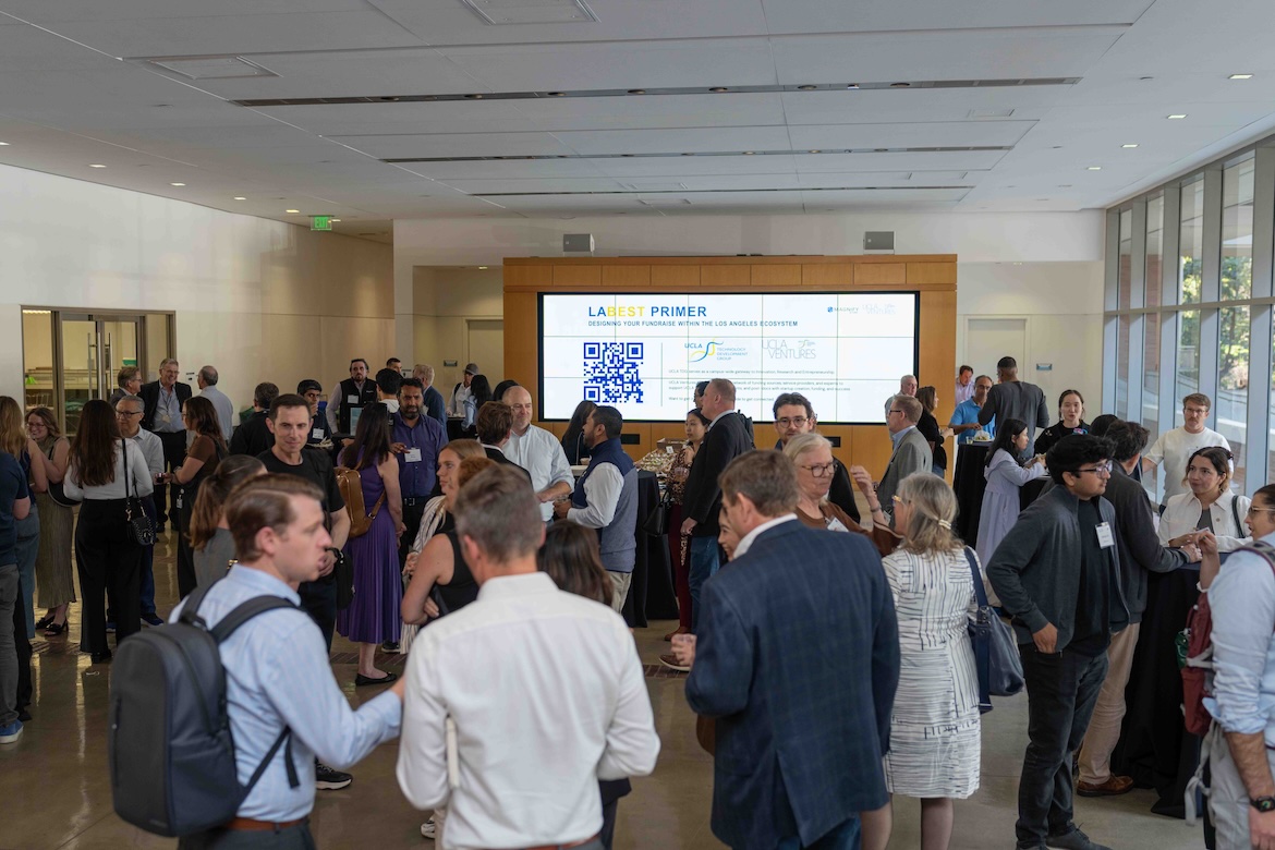Attendees mingle and network during UCLA’s LABEST Primer event in a bright conference space. Small groups converse around cocktail tables while a large digital display highlights entrepreneurship resources, startup support programs and fundraising opportunities within Los Angeles’ innovation ecosystem.