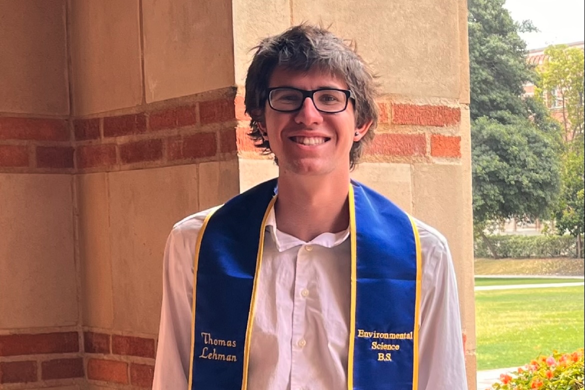 Thomas Lehman with graduation sash in Royce Hall portico, smiling