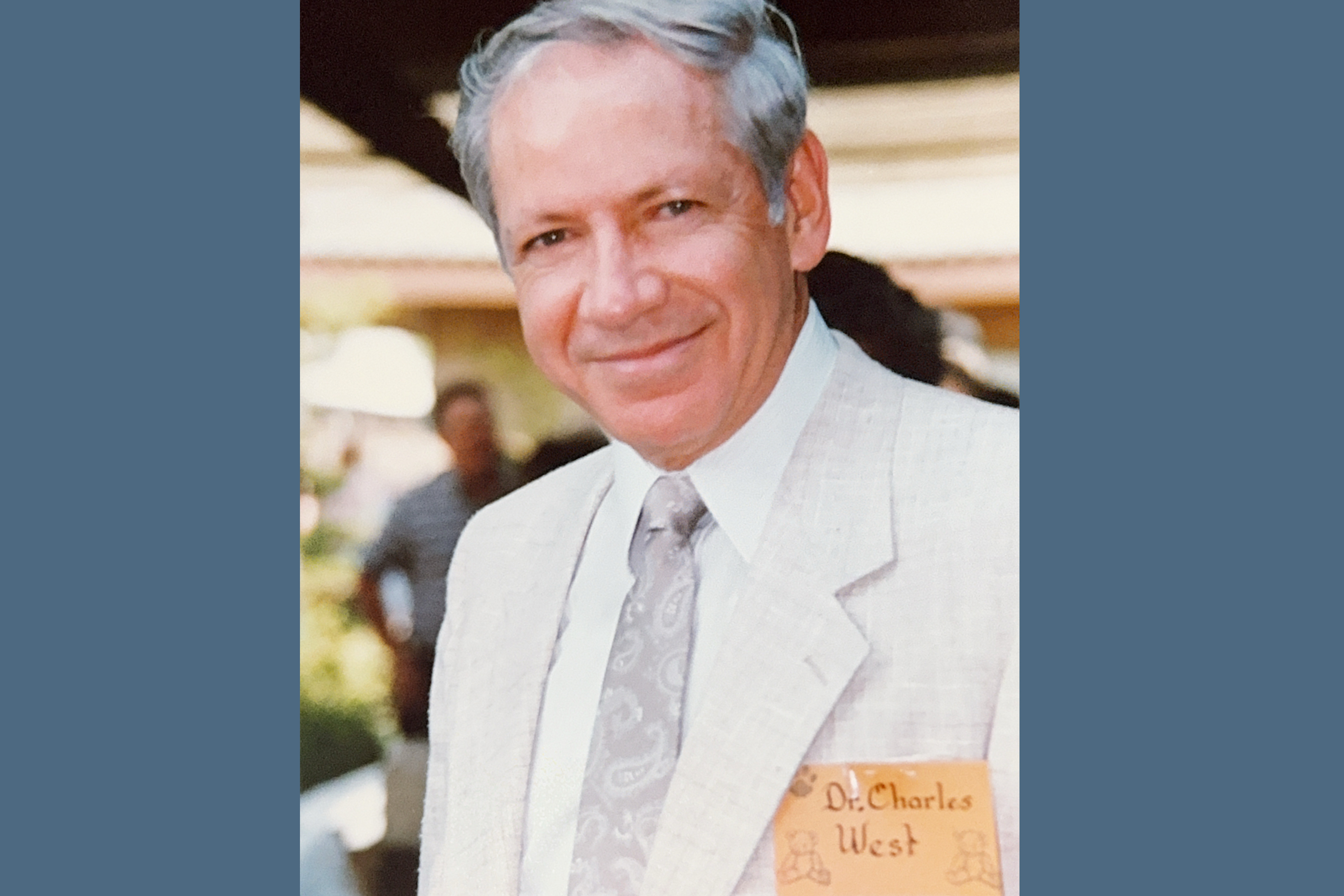Midrange photo of Charles West in light gray suit and tie