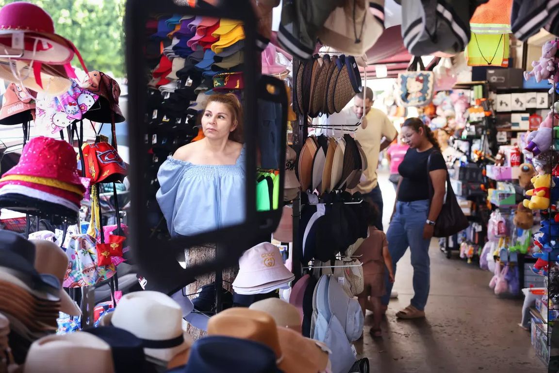 Fashion District shop owner Claudia Gonzalez waits for customers inside her store, where hats, bags and other merchandise line a narrow market aisle.