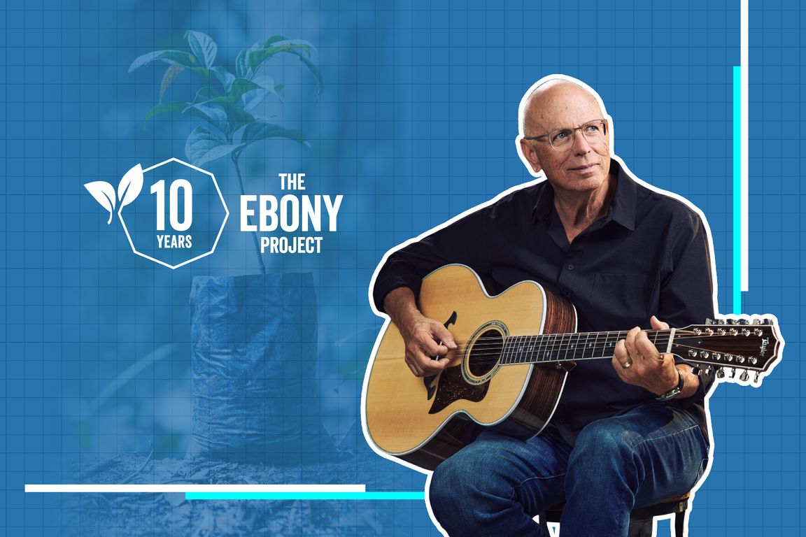 Taylor Guitars co-founder Bob Taylor sitting on a stool with a guitar against a blue grid background that features an Ebony Tree sapling