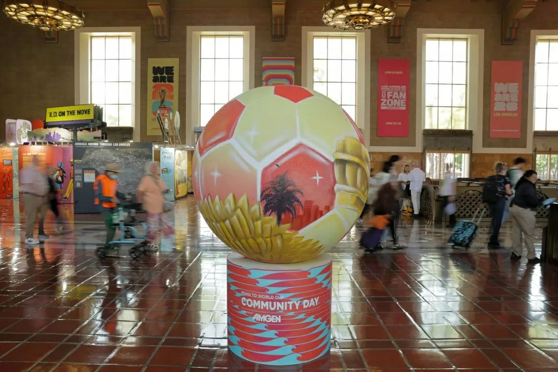 A large World Cup-themed soccer ball display stands in the center of Los Angeles Union Station as travelers pass through the station during the 2026 FIFA World Cup