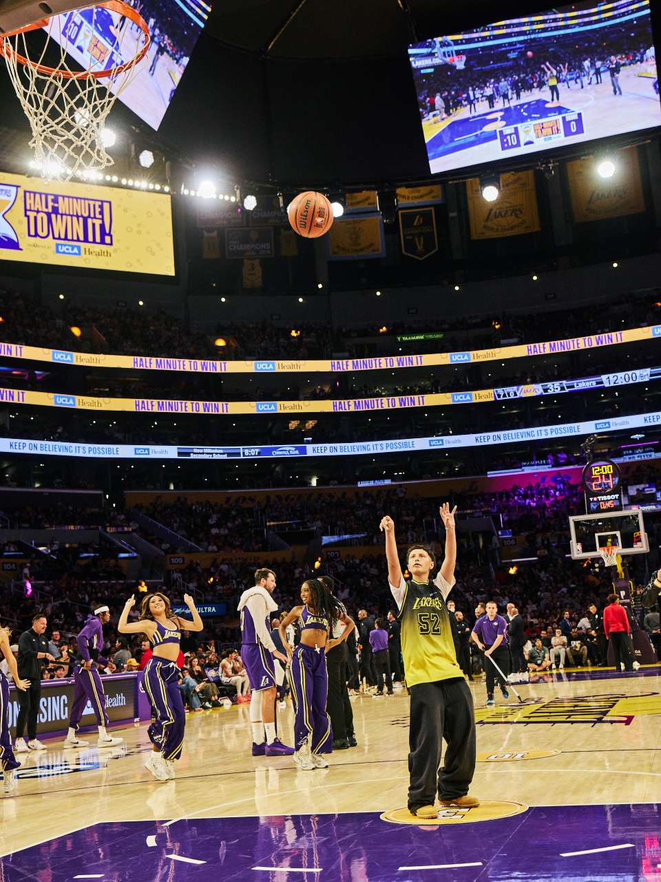Ava Hernandez, wearing a yellow Lakers jersey numbered 52, follows through on a free-throw attempt at center court at Crypto.com Arena.