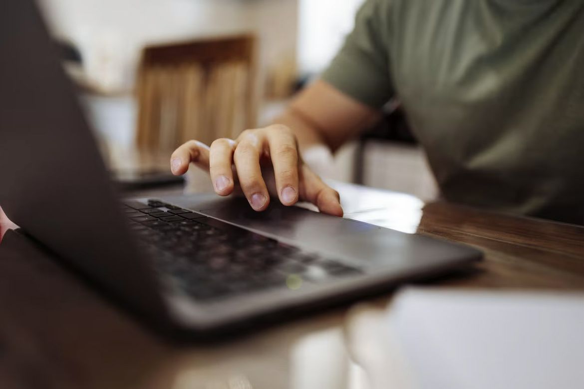 A person uses a laptop computer while seated at a table.