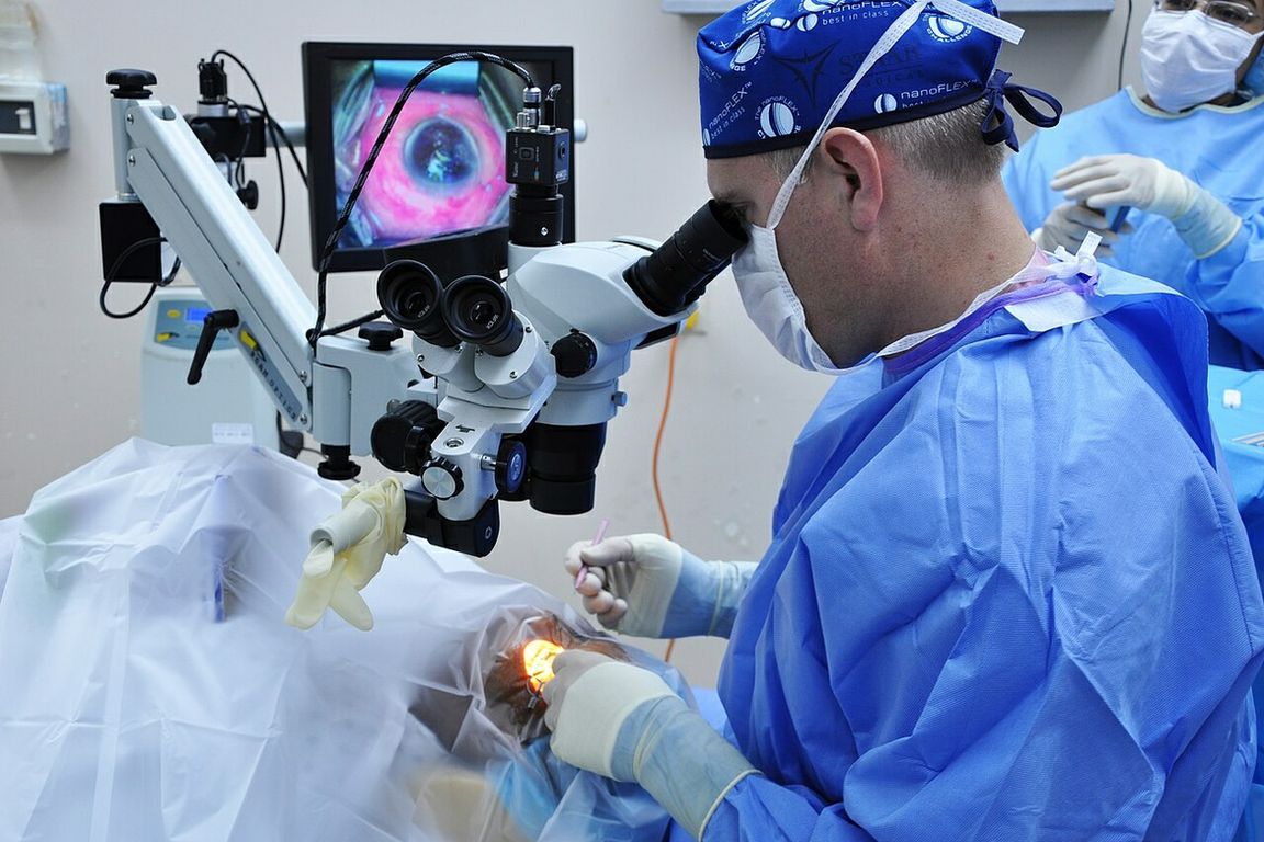 A physician uses a surgical microscope to perform traditional cataract surgery on a patient.